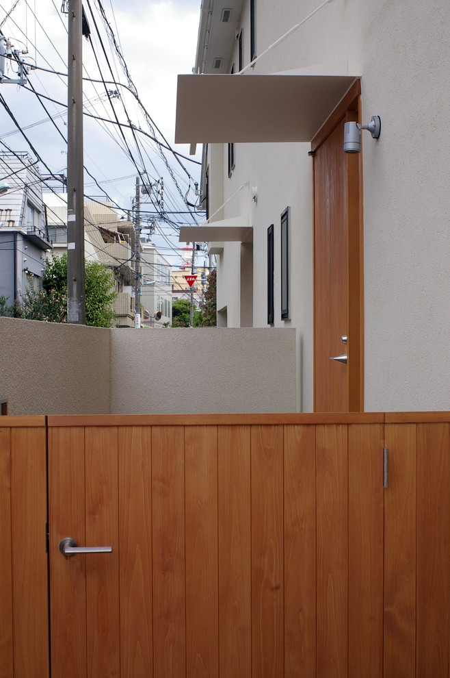 Réalisation d'une façade de maison mitoyenne beige minimaliste de taille moyenne et à un étage avec un toit à quatre pans.