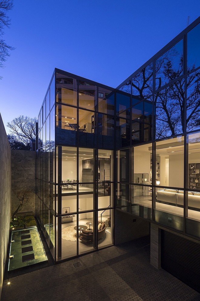 Cette image montre une façade de maison design en verre à deux étages et plus avec un toit plat.