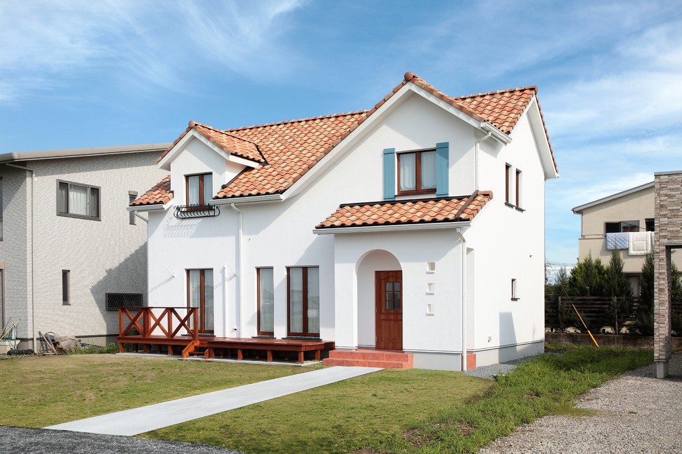 Cette photo montre une petite façade de maison blanche méditerranéenne en stuc avec un toit en tuile et un toit à deux pans.