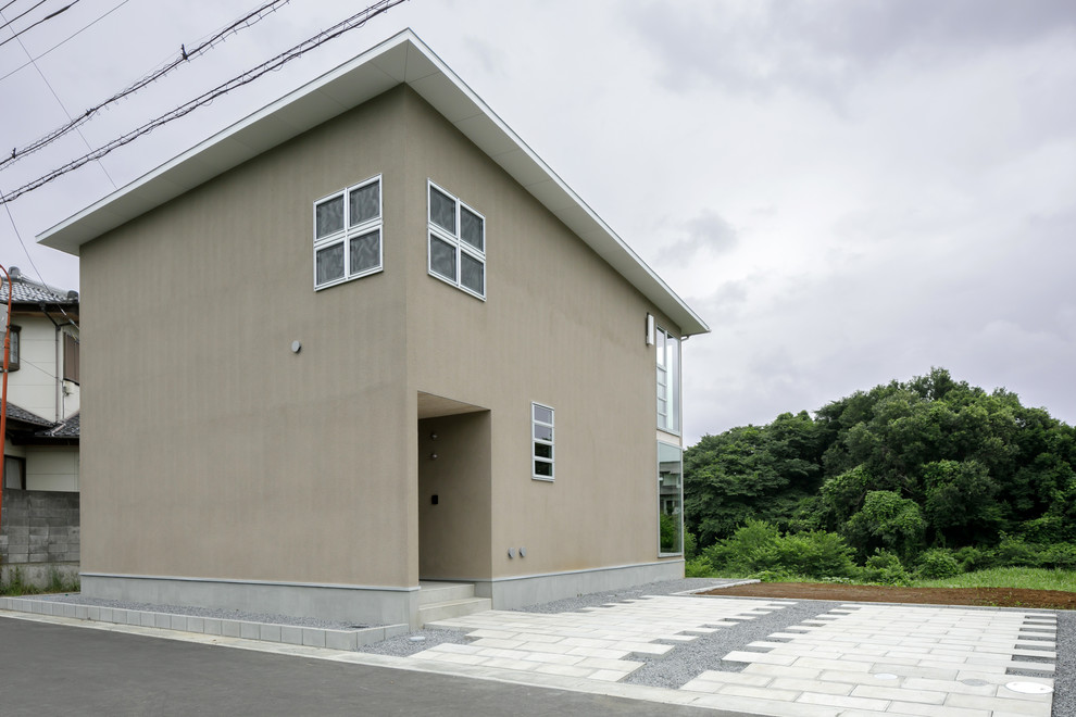 Cette image montre une façade de maison beige minimaliste à un étage et de taille moyenne avec un toit en appentis et un toit en métal.