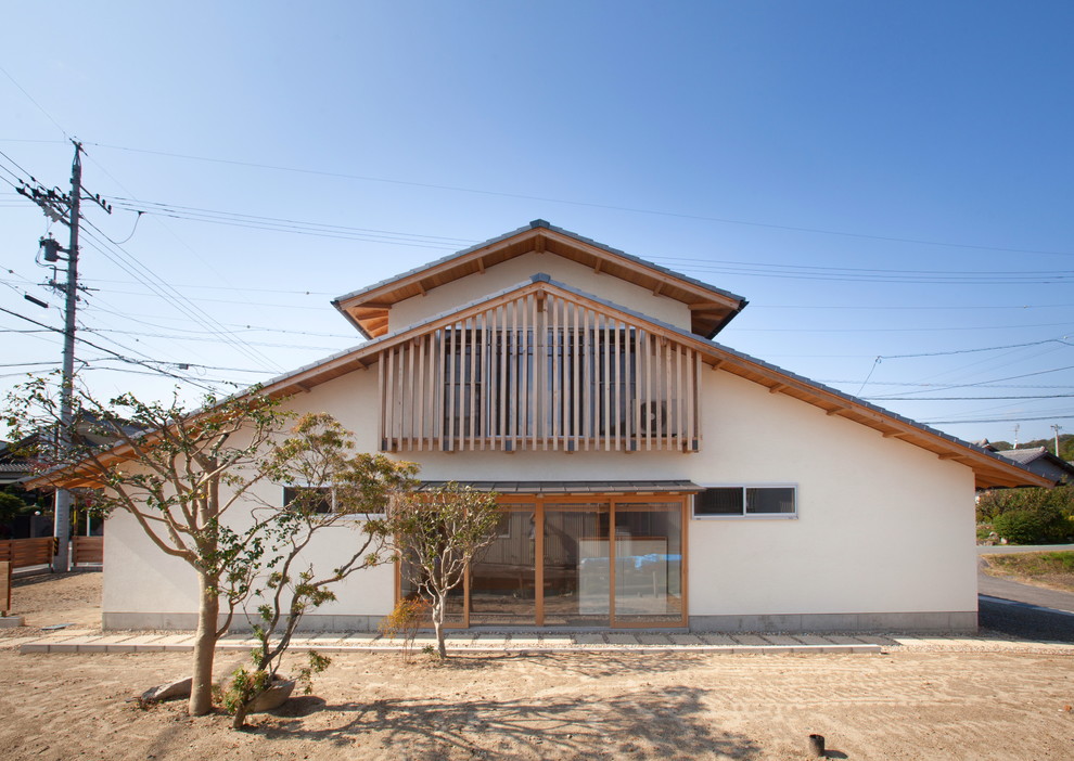 Cette image montre une façade de maison blanche asiatique avec un toit à deux pans et un toit en tuile.