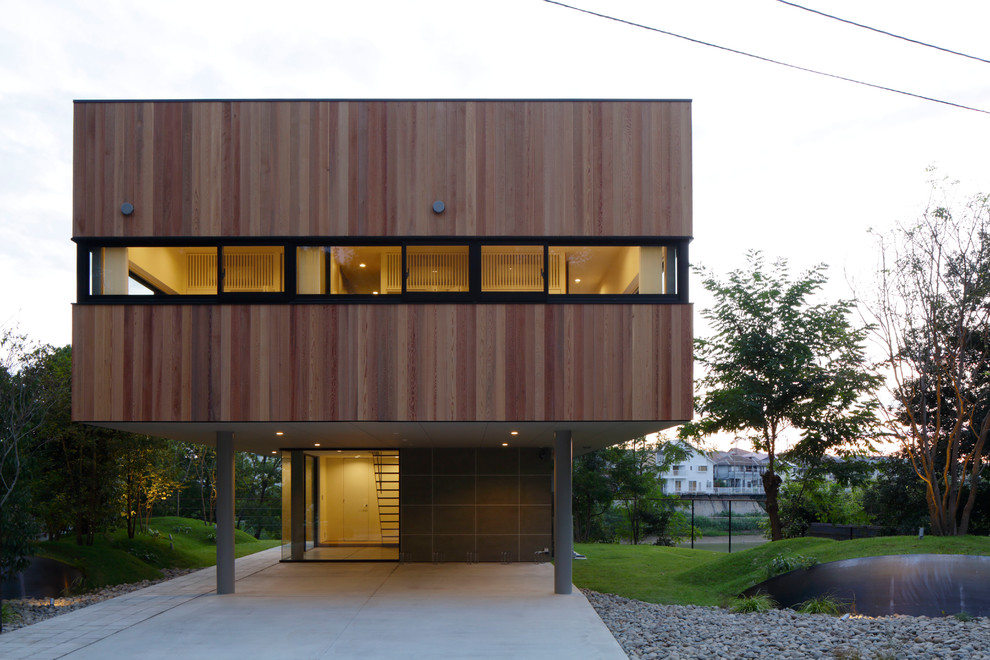 Esempio della facciata di una casa marrone moderna a due piani con rivestimento in legno e tetto piano