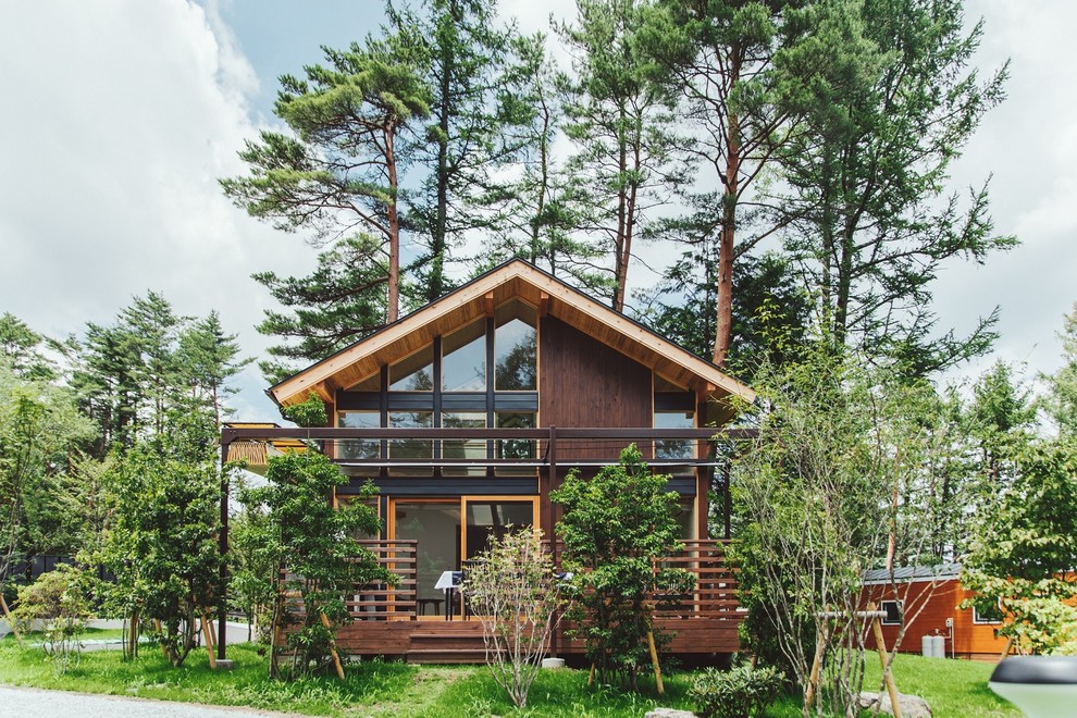 Kleine Landhausstil Holzfassade Haus mit brauner Fassadenfarbe und Satteldach in Sonstige