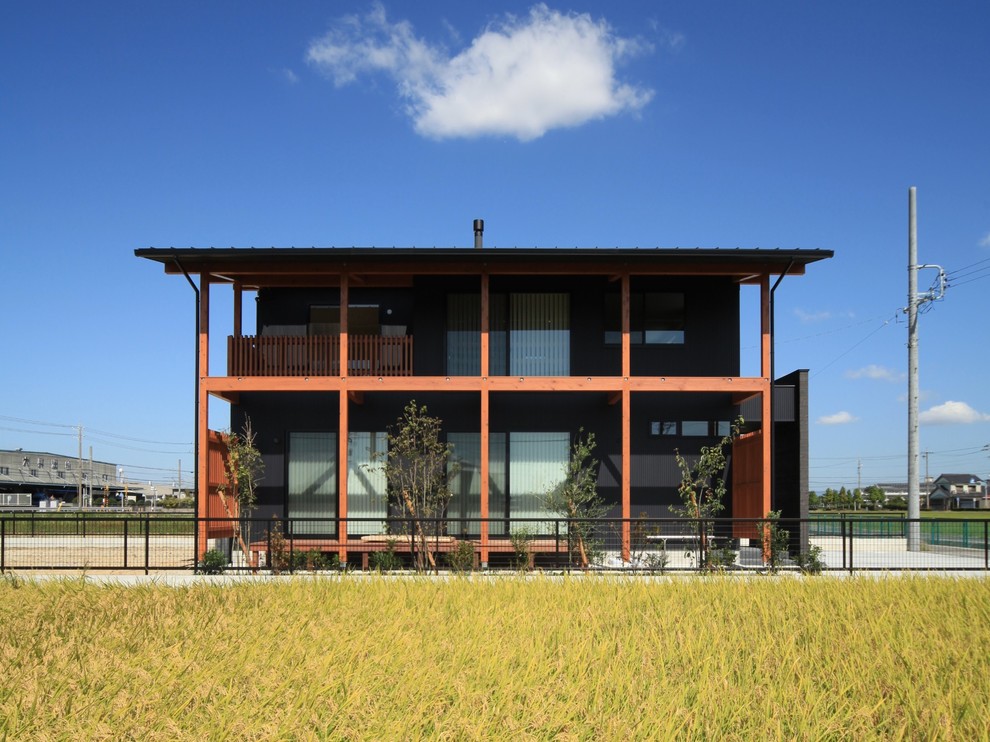 Cette image montre une façade de maison noire asiatique à un étage avec un toit en appentis et un toit en métal.