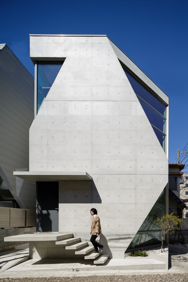Cette image montre une façade de maison grise design en béton à niveaux décalés avec un toit plat.