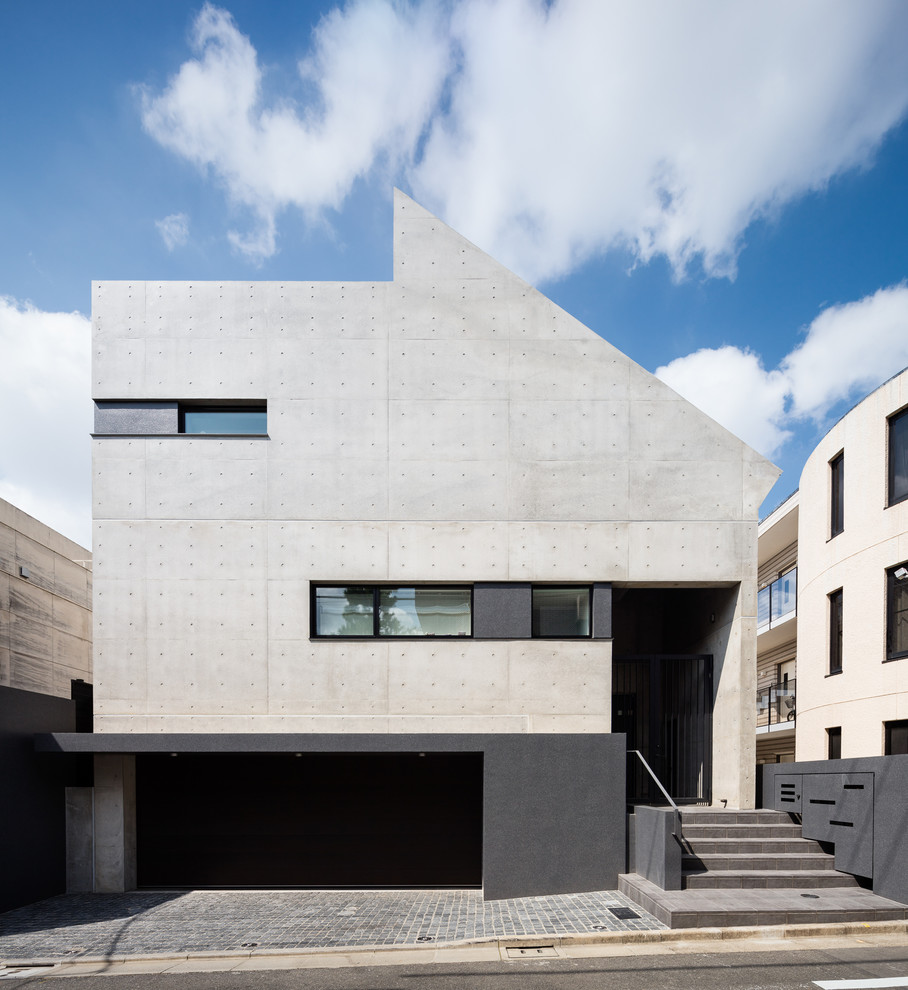 Cette photo montre une façade de maison grise moderne en béton à un étage avec un toit plat.