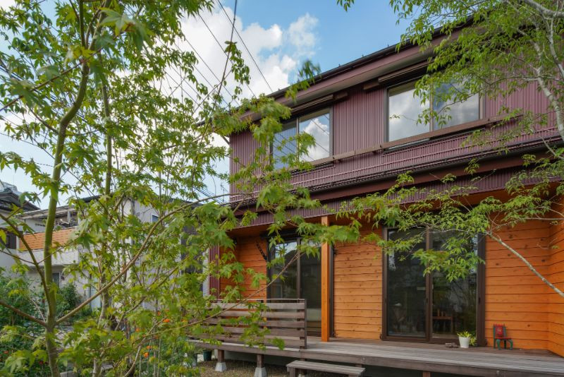 Идея дизайна: маленький, двухэтажный, деревянный, красный частный загородный дом в стиле кантри с двускатной крышей, металлической крышей, красной крышей и отделкой планкеном для на участке и в саду
