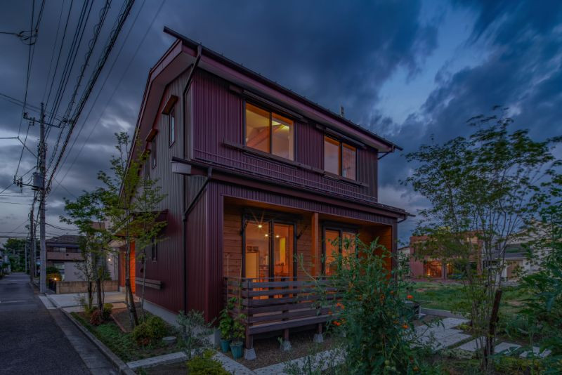 Esempio della villa piccola rossa american style a due piani con rivestimento in legno, tetto a capanna, copertura in metallo o lamiera, tetto rosso e pannelli sovrapposti