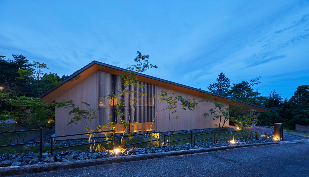 Imagen de fachada de casa beige actual de una planta con revestimiento de madera y tejado a dos aguas