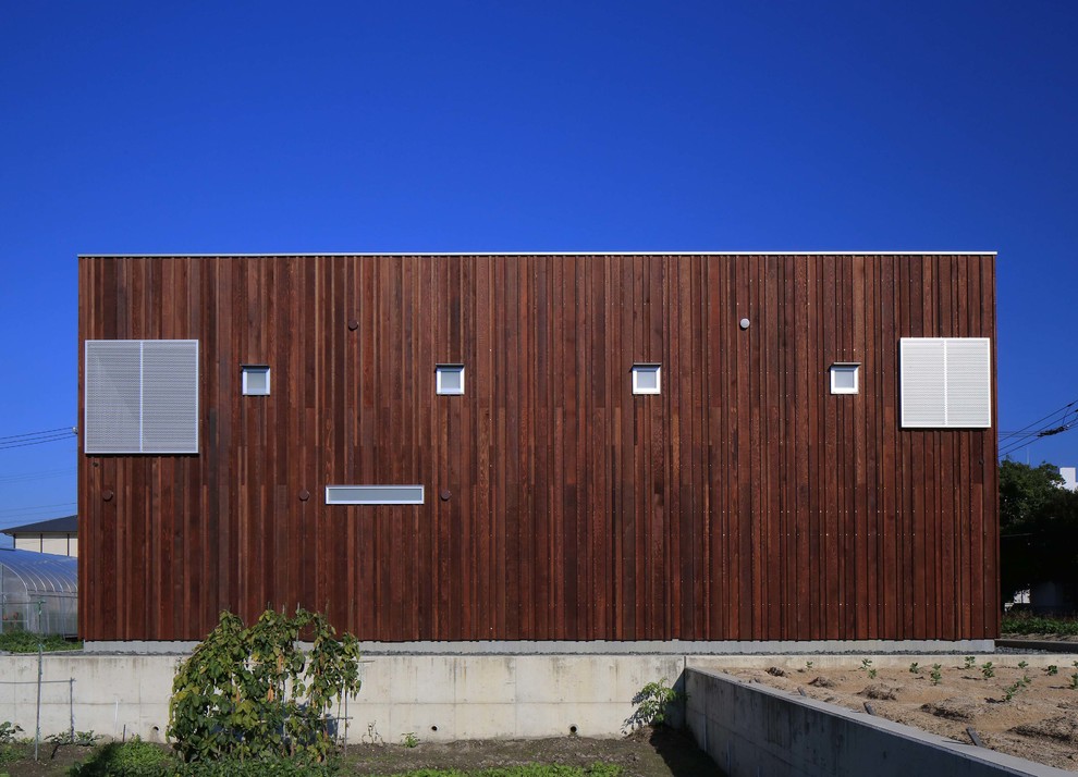 Idee per la facciata di una casa marrone moderna con rivestimento in legno e tetto piano