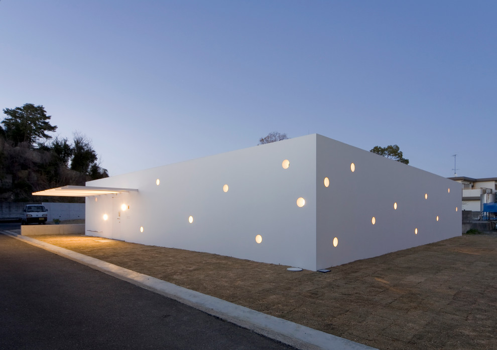 Réalisation d'une façade de maison blanche design de plain-pied avec un toit plat.