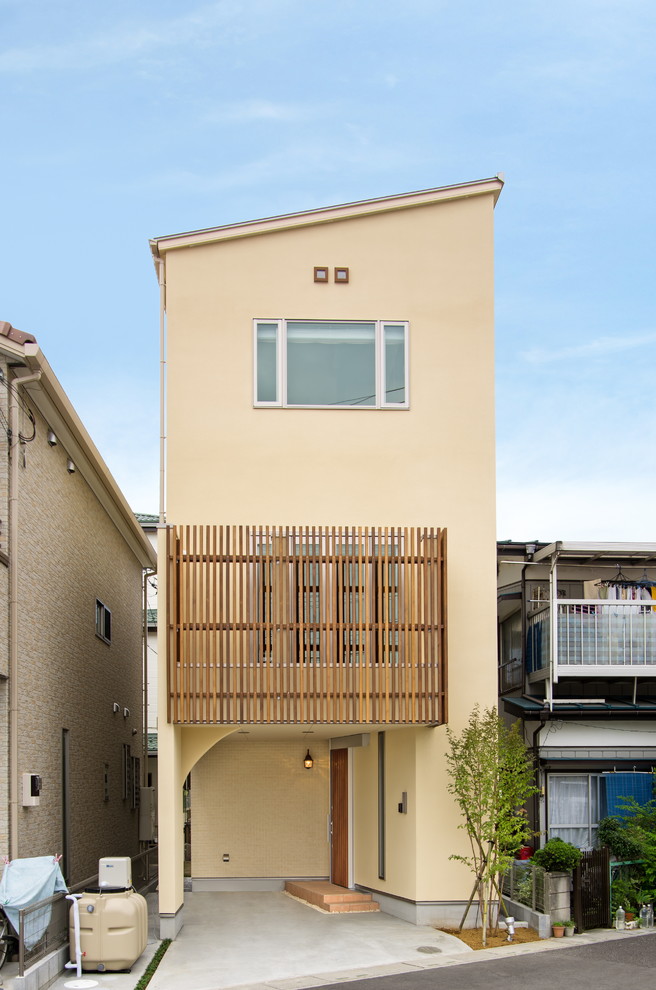 Cette image montre une façade de maison beige asiatique avec un toit en appentis.