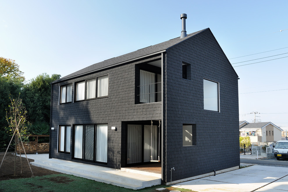 Imagen de fachada de casa negra asiática de dos plantas con tejado a dos aguas y tejado de teja de madera