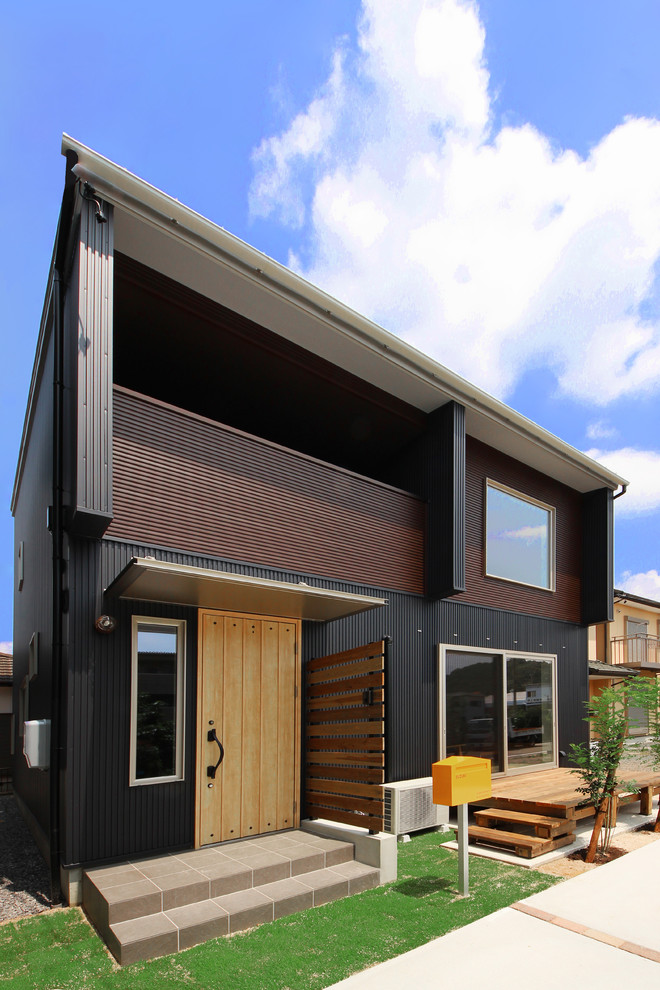 На фото: двухэтажный, черный дом в современном стиле с плоской крышей с