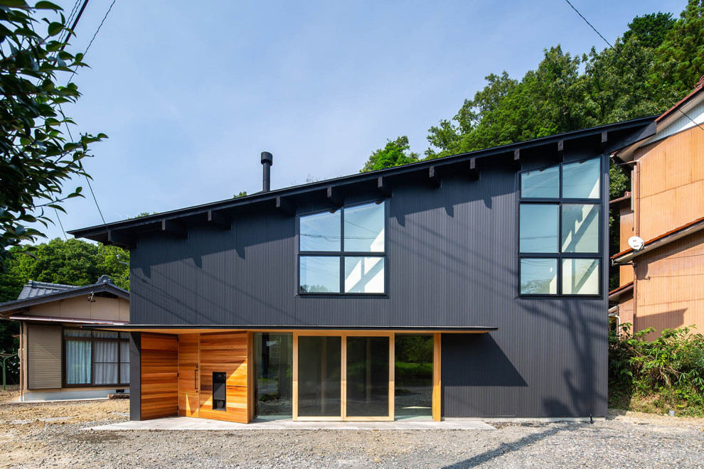 Cette image montre une petite façade de maison noire asiatique en bois à un étage avec un toit en appentis et un toit en métal.