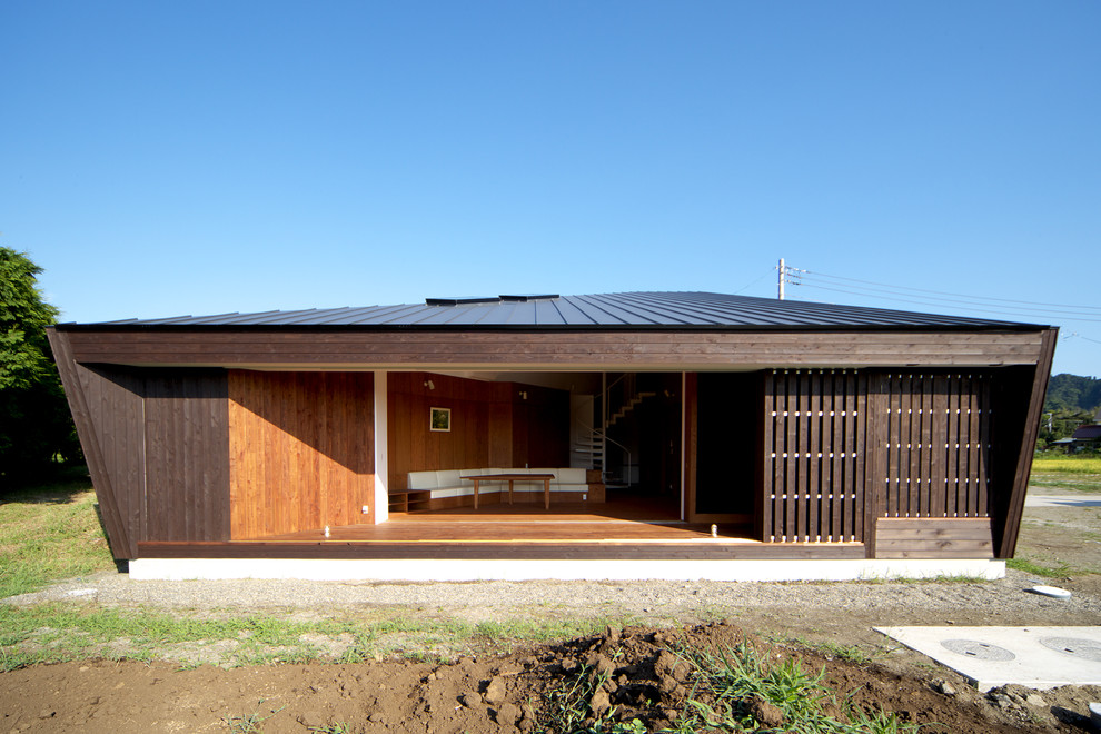 Imagen de fachada de casa marrón pequeña de una planta con revestimiento de madera, tejado plano y tejado de metal