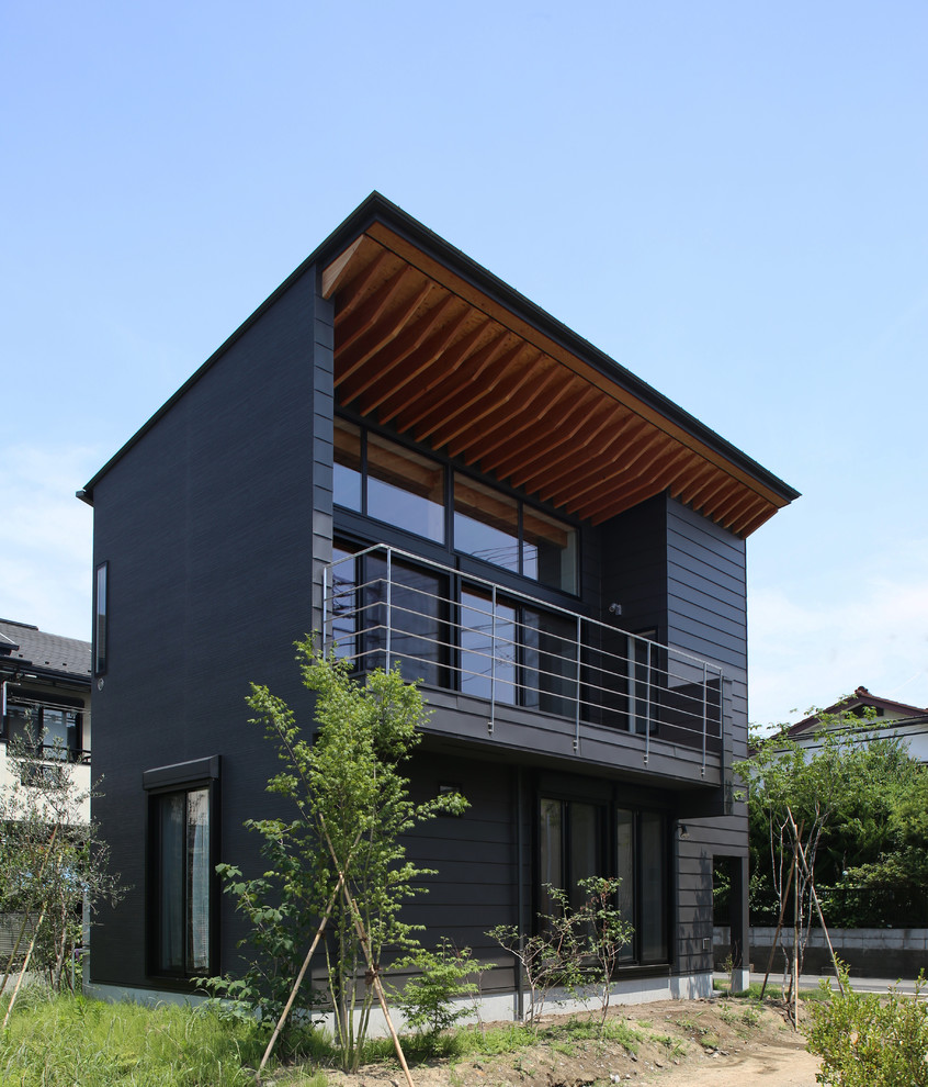 На фото: маленький, двухэтажный, серый частный загородный дом в восточном стиле с односкатной крышей и металлической крышей для на участке и в саду