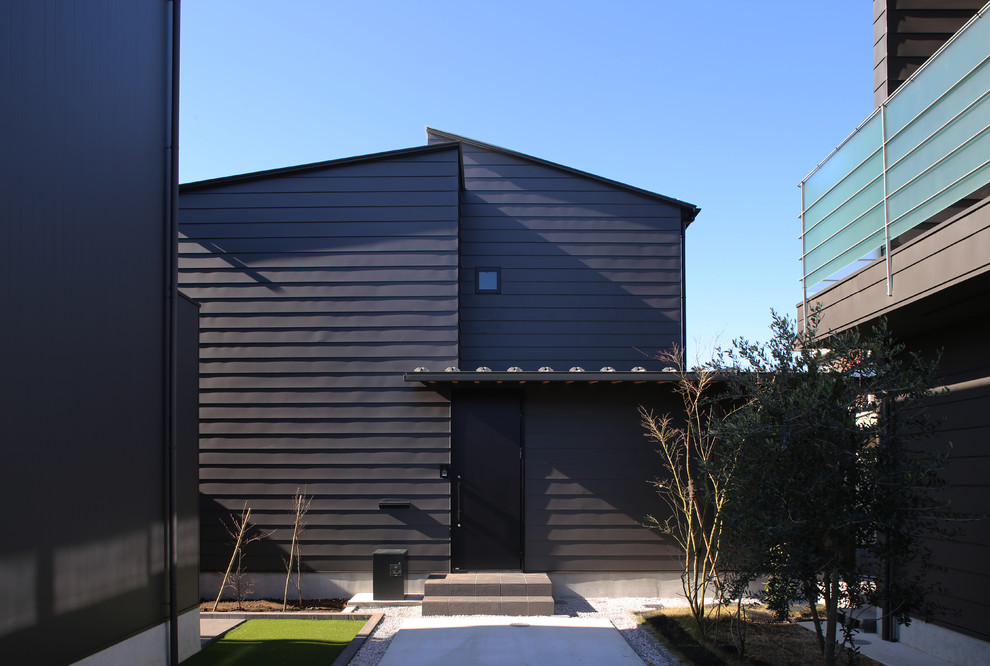 На фото: маленький, двухэтажный, черный частный загородный дом в стиле модернизм с односкатной крышей и металлической крышей для на участке и в саду
