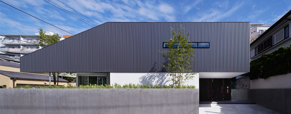 Cette photo montre une façade de maison grise moderne de taille moyenne et à un étage avec un toit plat et un toit blanc.