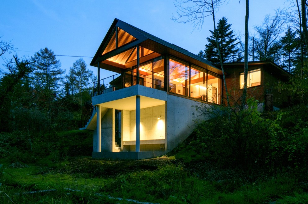 Diseño de fachada gris industrial de dos plantas con revestimiento de hormigón y tejado a dos aguas
