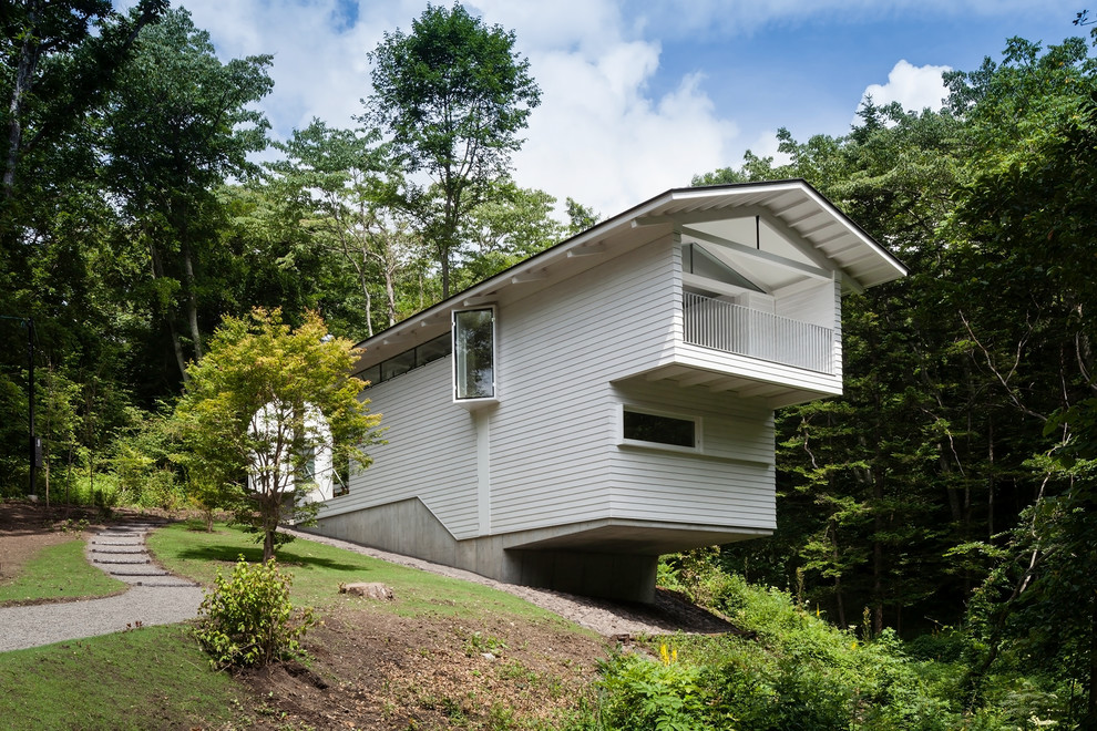 Exemple d'une façade de maison grise tendance à un étage avec un revêtement en vinyle, un toit à deux pans et un toit en métal.
