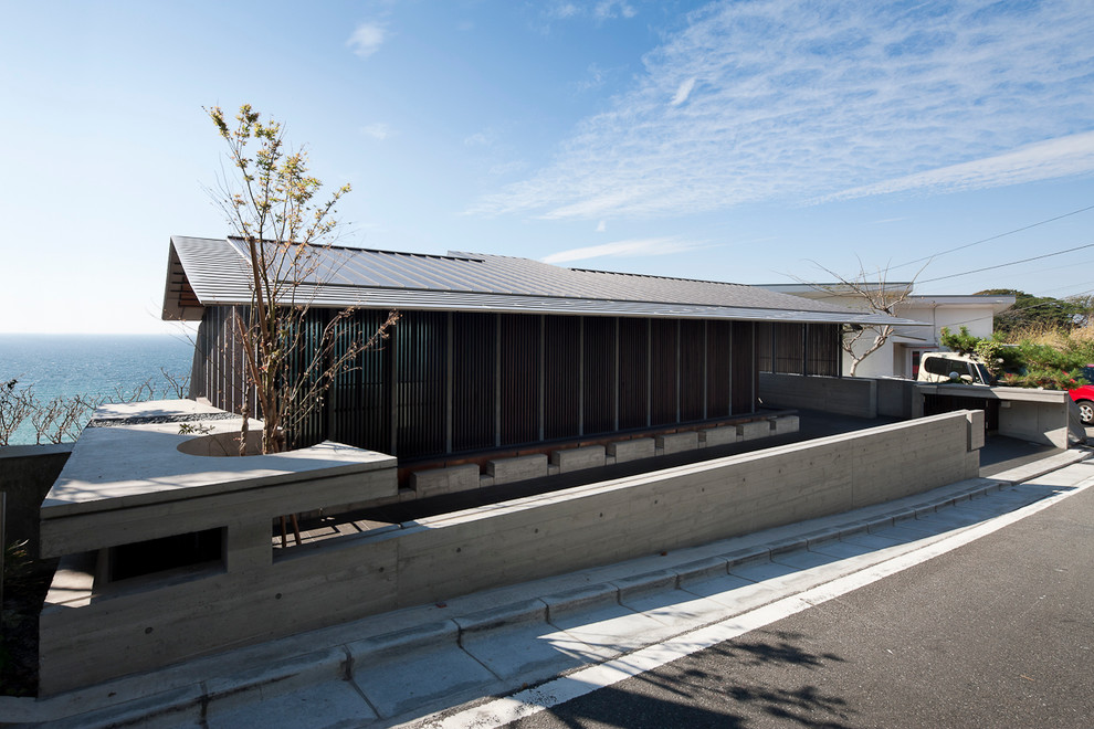 Diseño de fachada marrón de estilo zen con tejado a dos aguas y revestimiento de madera