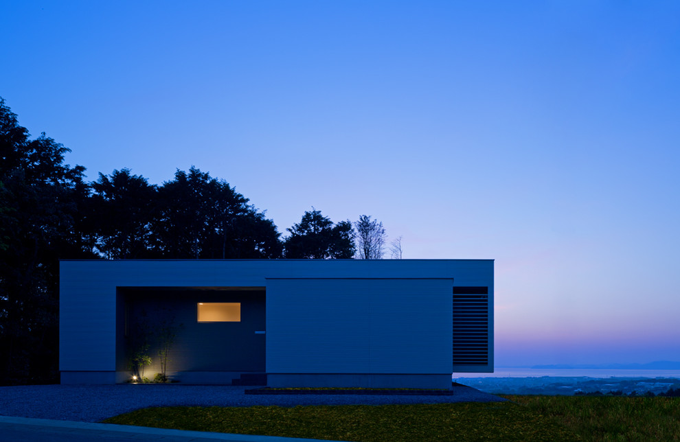 На фото: одноэтажный, серый дом в стиле модернизм с комбинированной облицовкой и плоской крышей с