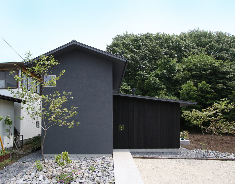 Modelo de fachada de casa negra minimalista de tamaño medio de dos plantas con tejado a dos aguas y tejado de metal