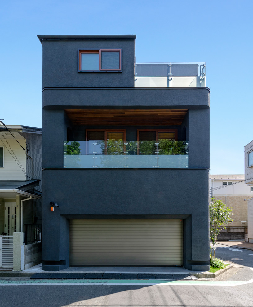 Medium sized and black modern split-level render detached house in Yokohama with a metal roof.