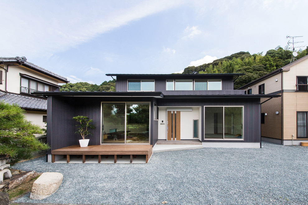 Aménagement d'une façade de maison noire asiatique à un étage avec un toit en métal et un toit plat.