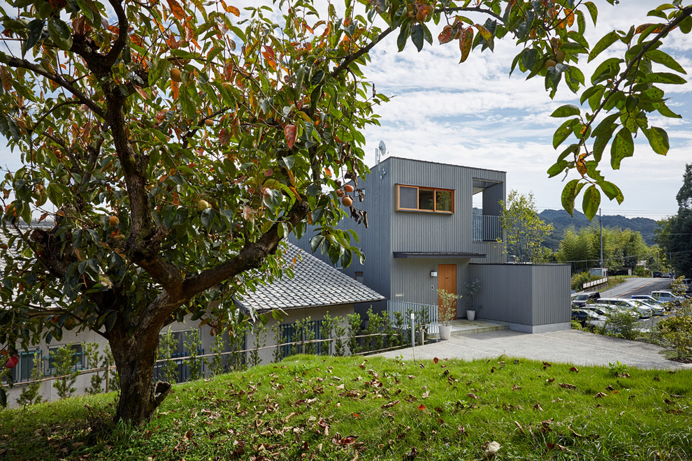 Réalisation d'une façade de maison grise asiatique en bois de taille moyenne et à deux étages et plus avec un toit en appentis et un toit en métal.