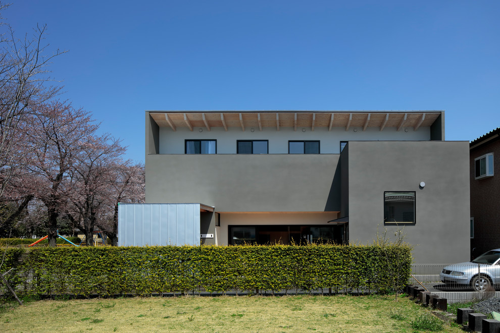 Idée de décoration pour une façade de maison grise minimaliste à un étage avec un toit en appentis et un toit en métal.