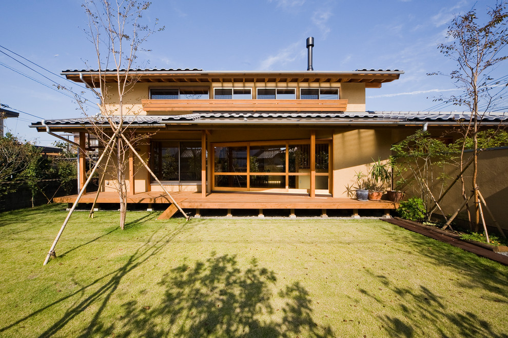 На фото: двухэтажный, коричневый частный загородный дом в японском стиле в восточном стиле с двускатной крышей и черепичной крышей