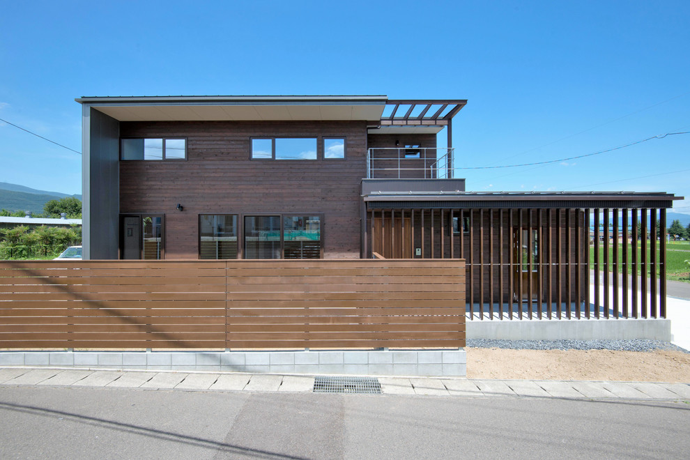 This is an example of a brown contemporary two floor house exterior in Other with wood cladding.