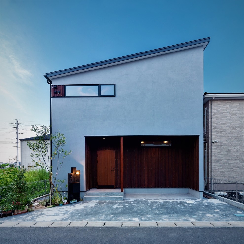 Cette image montre une façade de maison grise design avec un toit en appentis.