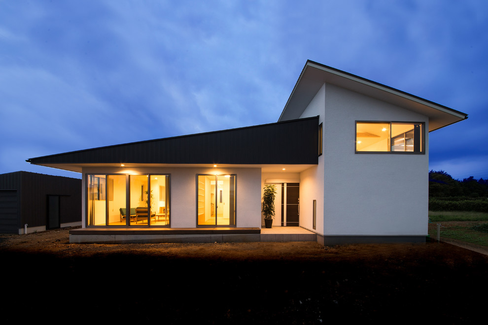 Idée de décoration pour une façade de maison blanche minimaliste en stuc de plain-pied avec un toit en appentis et un toit en métal.