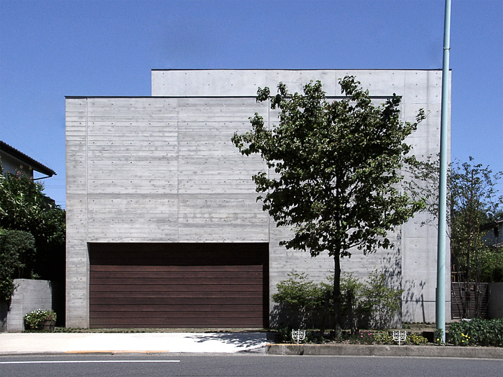 Diseño de fachada gris actual de dos plantas con revestimiento de hormigón y tejado plano