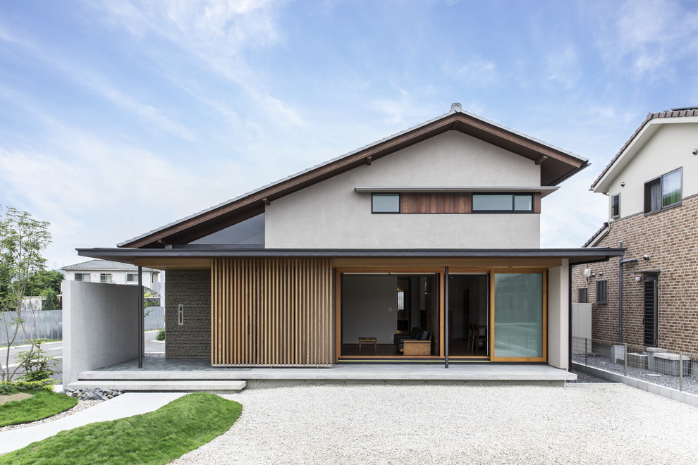 Свежая идея для дизайна: двухэтажный, серый частный загородный дом в восточном стиле с комбинированной облицовкой и двускатной крышей - отличное фото интерьера