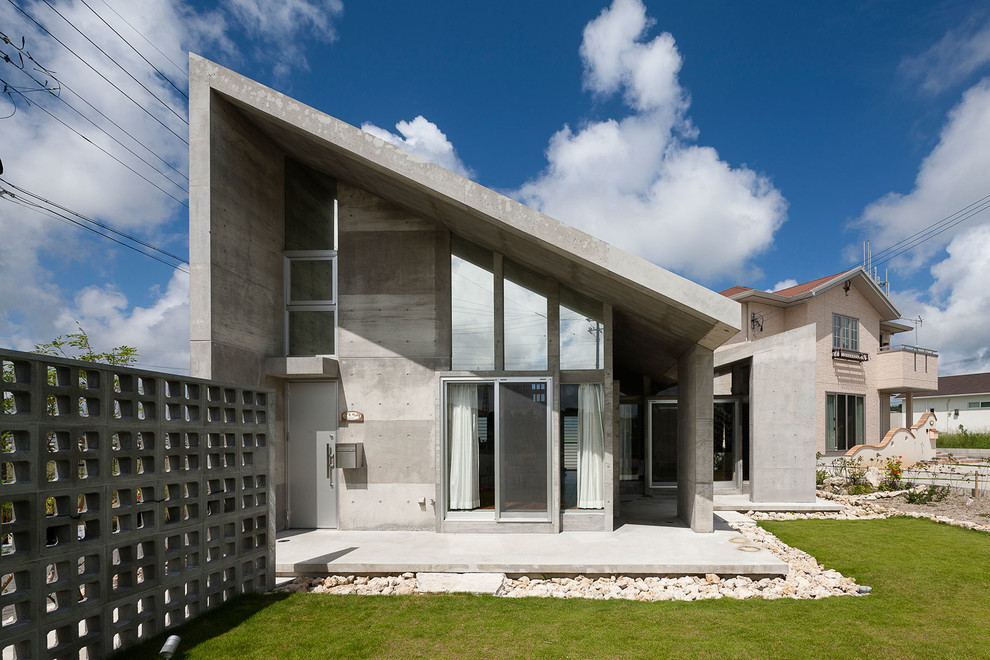 Cette image montre une façade de maison grise urbaine en béton à un étage avec un toit en appentis.