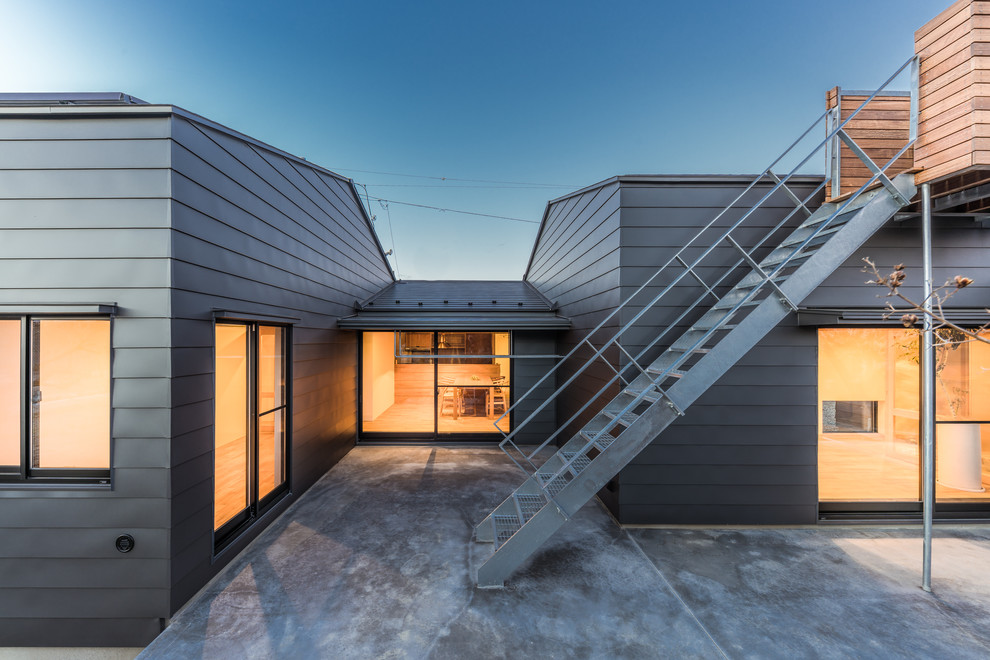 Inspiration pour une très grande façade de maison métallique et grise design de plain-pied avec un toit à deux pans et un toit en métal.