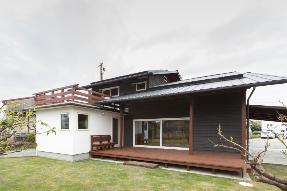 Cette image montre une façade de maison grise asiatique en bois de taille moyenne et à un étage avec un toit à deux pans.