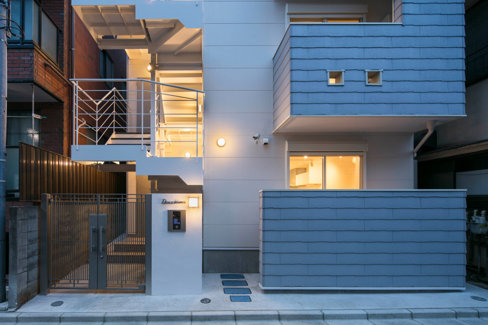 Идея дизайна: трехэтажный, серый многоквартирный дом среднего размера в скандинавском стиле с облицовкой из ЦСП, полувальмовой крышей и металлической крышей
