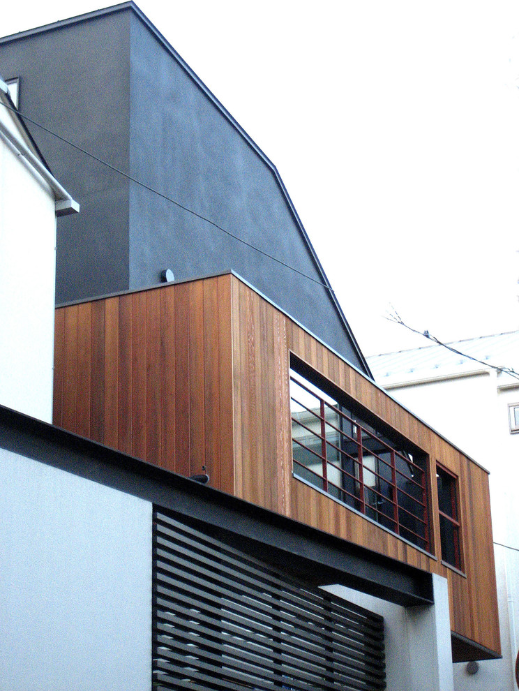 Foto på ett mellanstort funkis grått hus, med två våningar, pulpettak och tak i metall