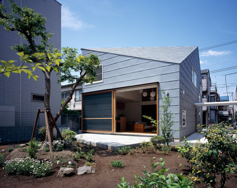 Immagine della facciata di una casa piccola blu a due piani con tetto a capanna