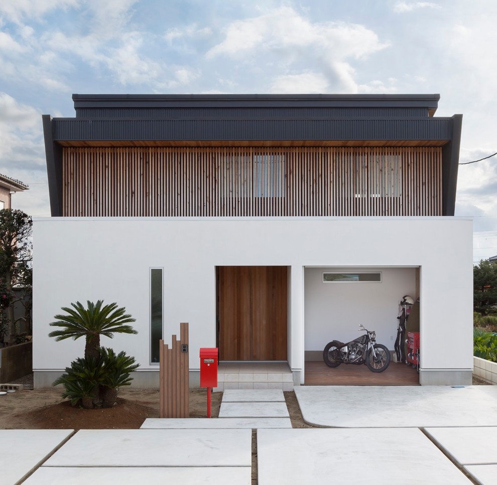 Réalisation d'une façade de maison blanche asiatique à un étage avec un revêtement mixte, un toit plat et boîte aux lettres.