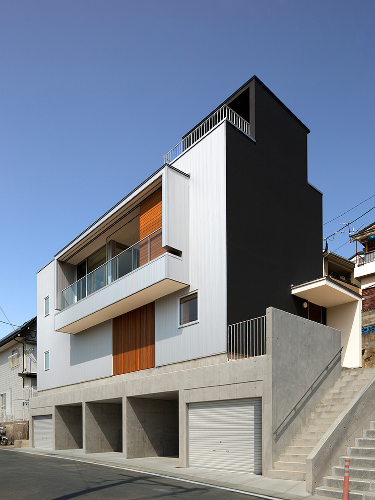 Inspiration pour une petite façade de maison métallique et noire minimaliste à un étage avec un toit plat.