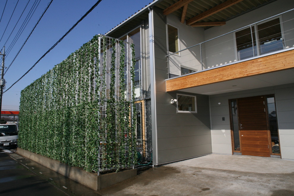 Cette photo montre une façade de maison métallique et grise moderne de taille moyenne et à un étage avec un toit à deux pans et un toit en métal.