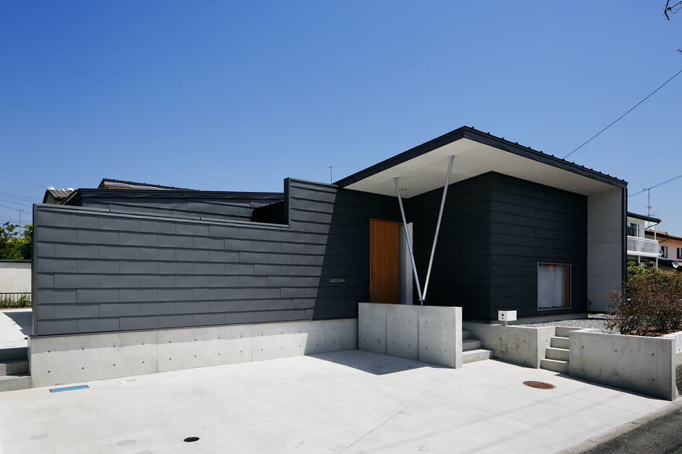 Foto på ett funkis grått hus, med allt i ett plan, pulpettak och tak i metall