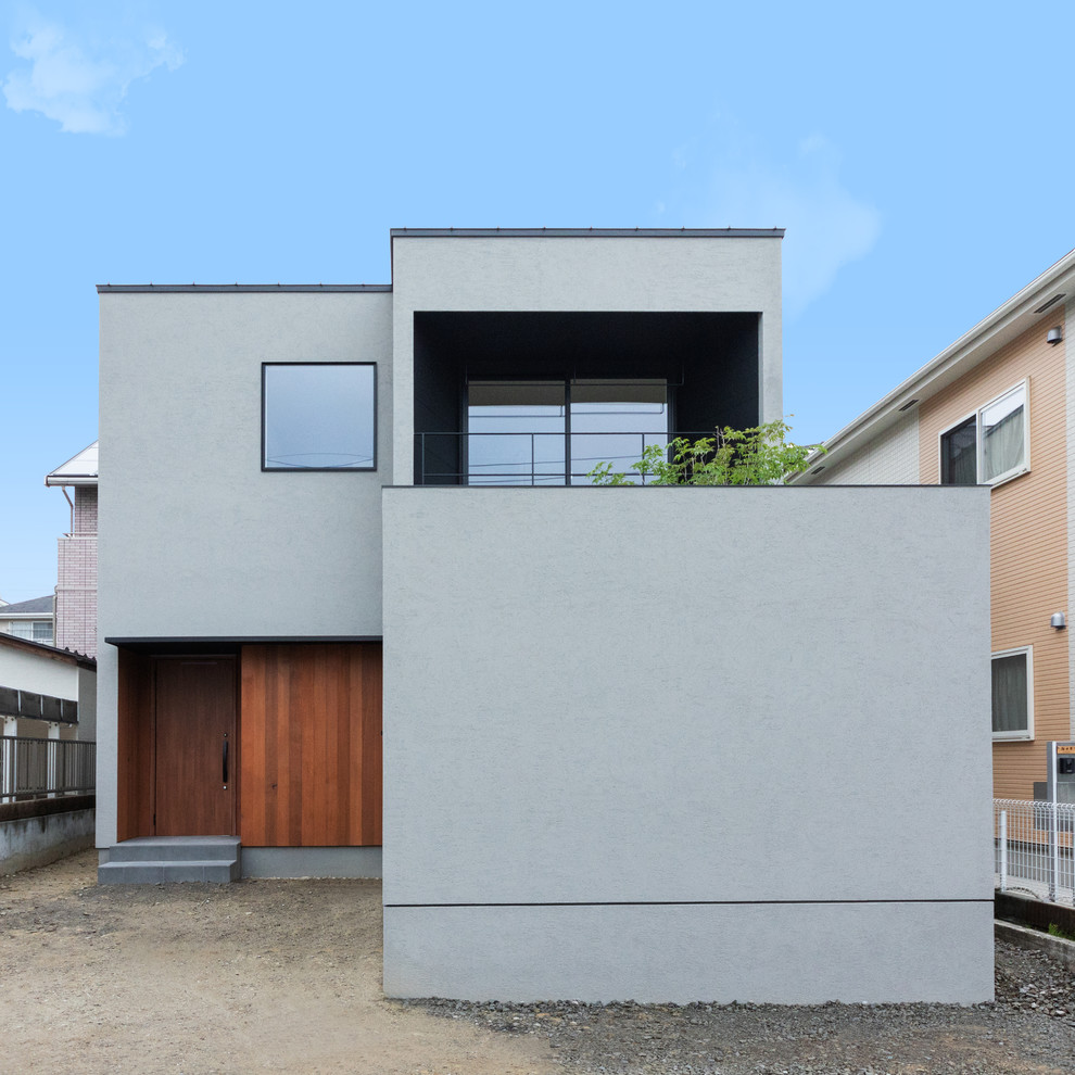 Réalisation d'une façade de maison grise design avec un toit plat.