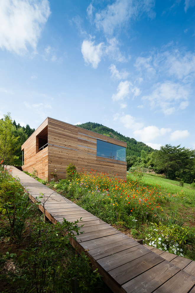 Kleine Moderne Holzfassade Haus mit brauner Fassadenfarbe und Flachdach in Sonstige
